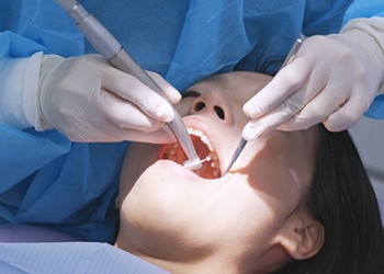 A dentist working on a female patient’s mouth