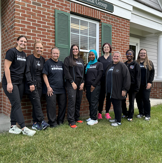 The smiling Powell Dental Group team standing in front of the dental office
