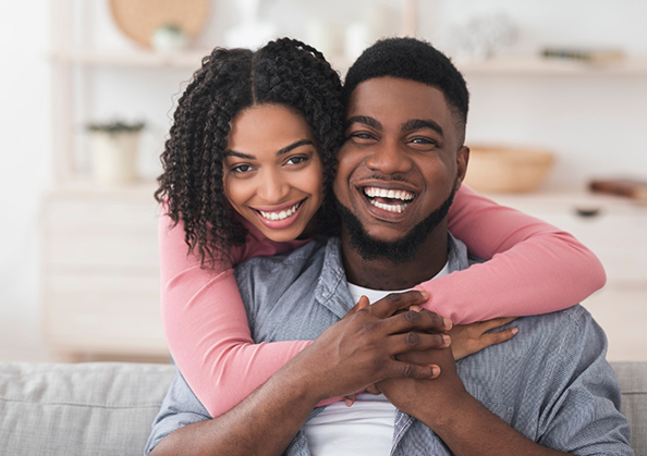 Smiling man and woman embracing on their couch