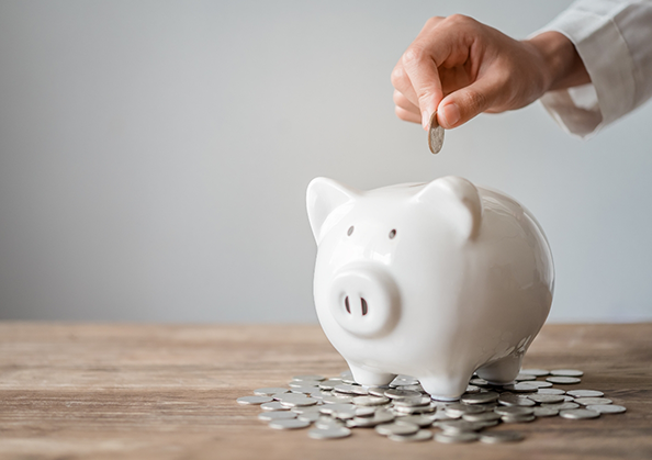 Hand placing a coin in a piggy bank