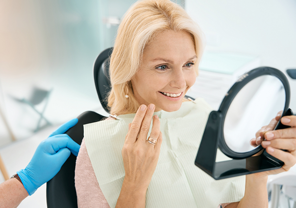 Dental patient looking at her smile in a mirror