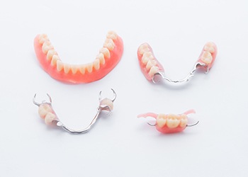 A lower full denture and three various types of partial dentures lying on a table