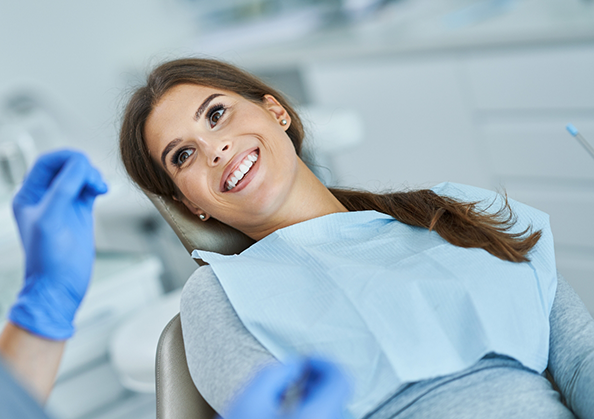 Woman in the treatment chair smiling at her dentist