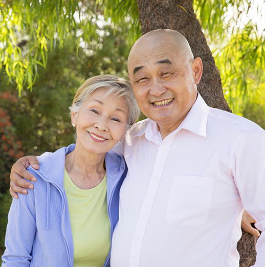 Older man and woman smiling outdoors after replacing missing teeth in Powell