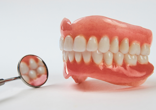 Full dentures next to a dental mirror
