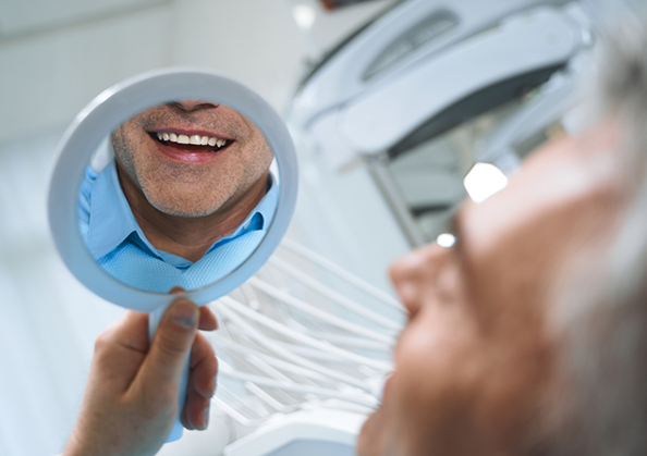 Dental patient admiring his smile in a mirror