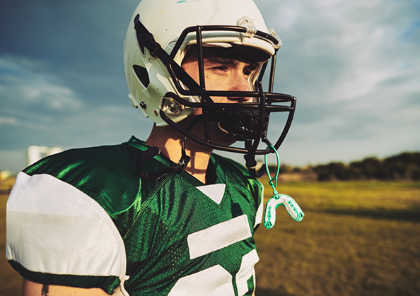 Football player with a mouthguard hanging from their helmet