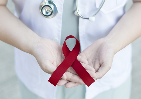 Doctor holding a red ribbon for oral cancer awareness