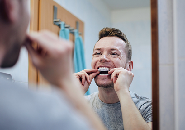 Man using a teeth whitening tray at home
