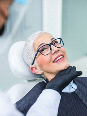 Woman with black glasses smiling at dentist