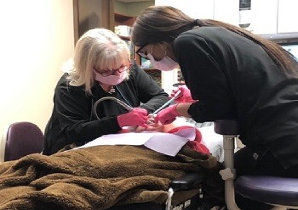 Doctor Shults and an assistant treating a dental patient