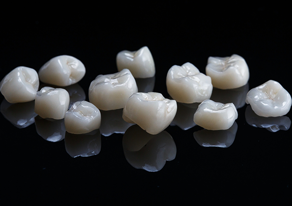 Several white dental crowns against a black background